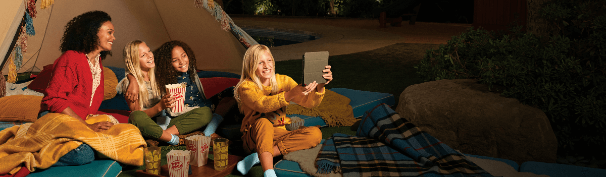 A family camping outside and watching a video on a tablet device